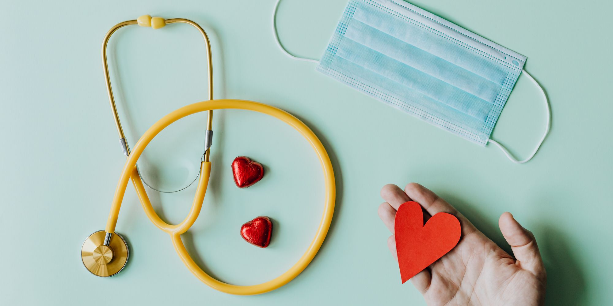Yellow stethoscope and red hearts on a mint background for World Heart Day